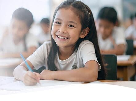 A child smiling in a classroom, supported by CareHub donors